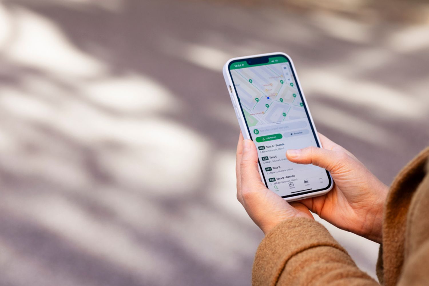 Hand hält Smartphone mit Karte auf dem Display, neutraler Hintergrund
