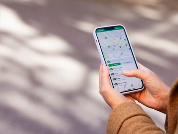 Hand hält Smartphone mit Karte auf dem Display, neutraler Hintergrund