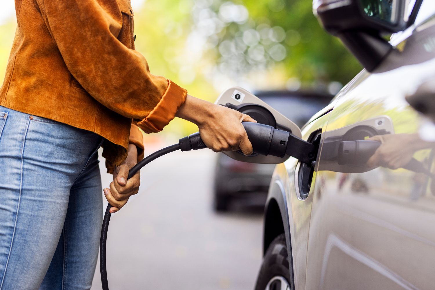 Person holds charging cable to charge electric vehicle