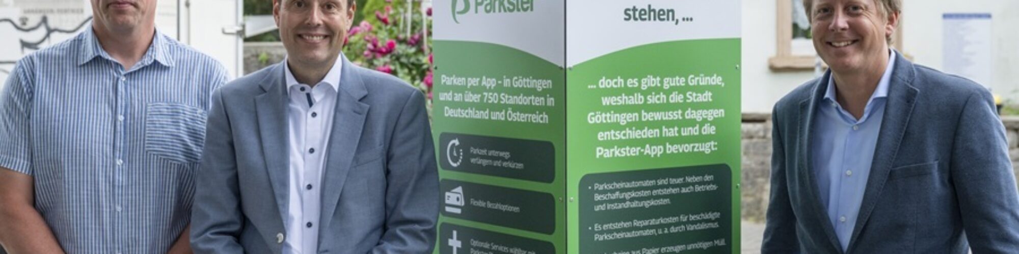 von links nach rechts: Herr Baye und Herr Schmetz von der Stadt Göttingen sowie Herr Lundberg stehen neben einer rechteckigen Säule mit Informationen über Parkster