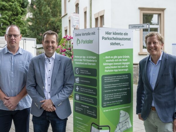 von links nach rechts: Herr Baye und Herr Schmetz von der Stadt Göttingen sowie Herr Lundberg stehen neben einer rechteckigen Säule mit Informationen über Parkster