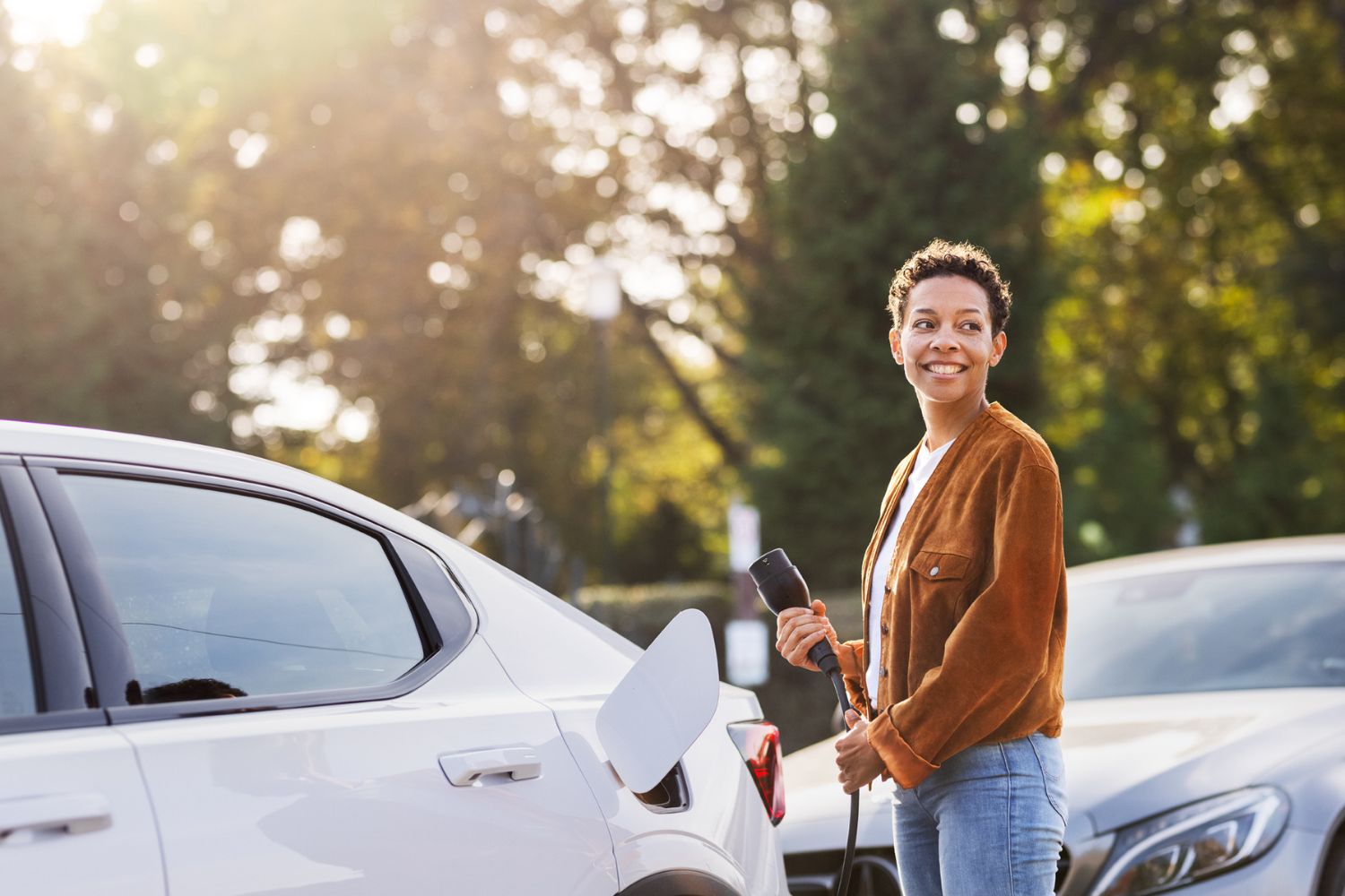En kvinna ler och laddar sin el-bil