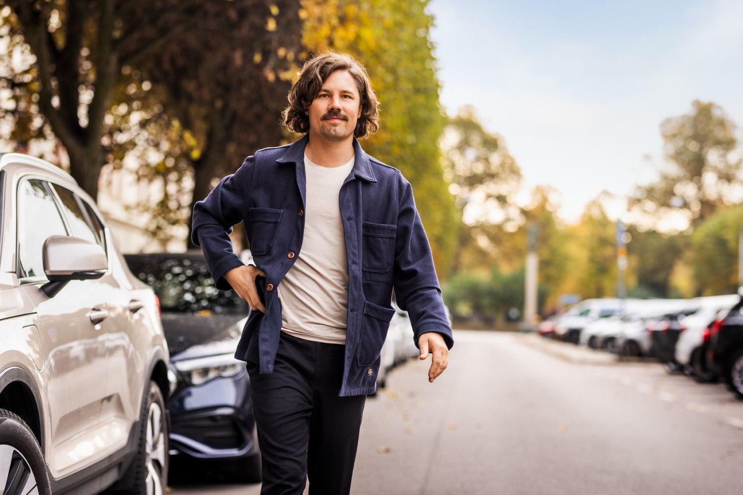 En man går utanför sin bil med en mobil i handen