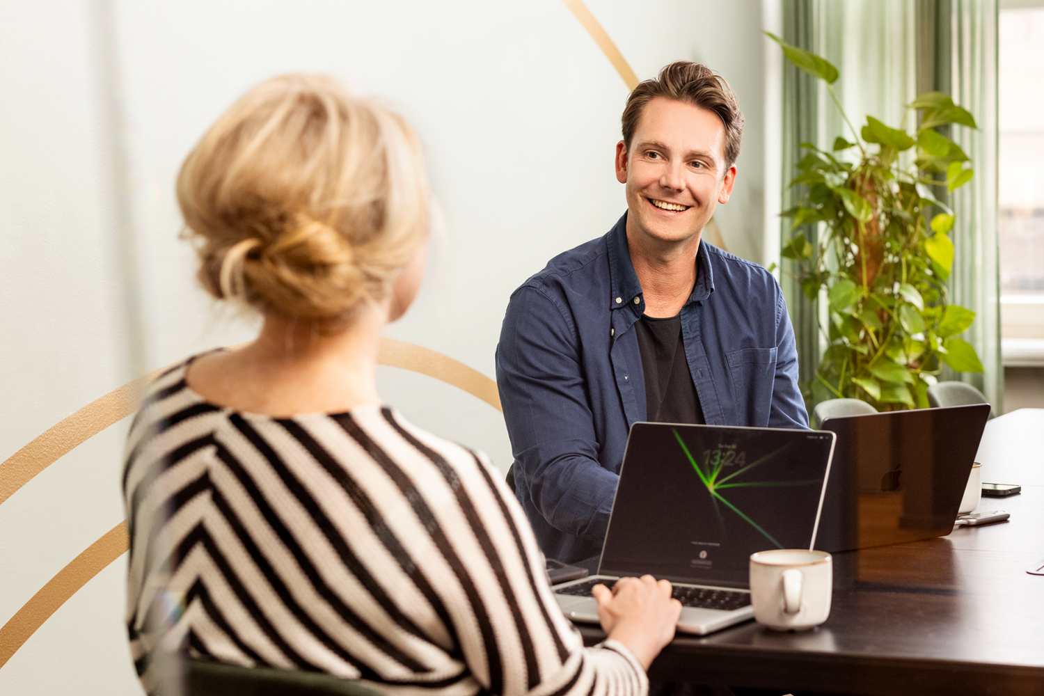 En man tittar på en kvinna i ett mötesrum. De skrattar och arbetar tillsammans.