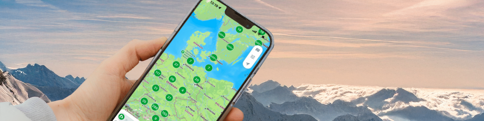 Någon håller en mobiltelefon med alperna i bakgrunden