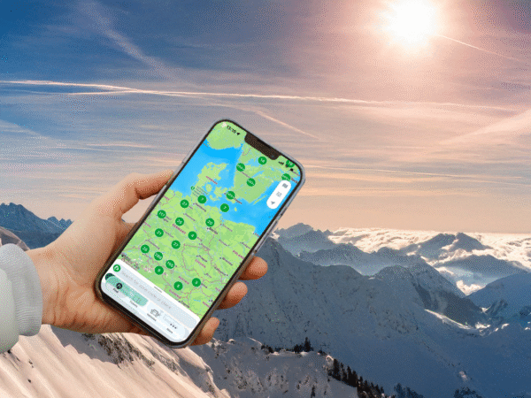 Någon håller en mobiltelefon med alperna i bakgrunden