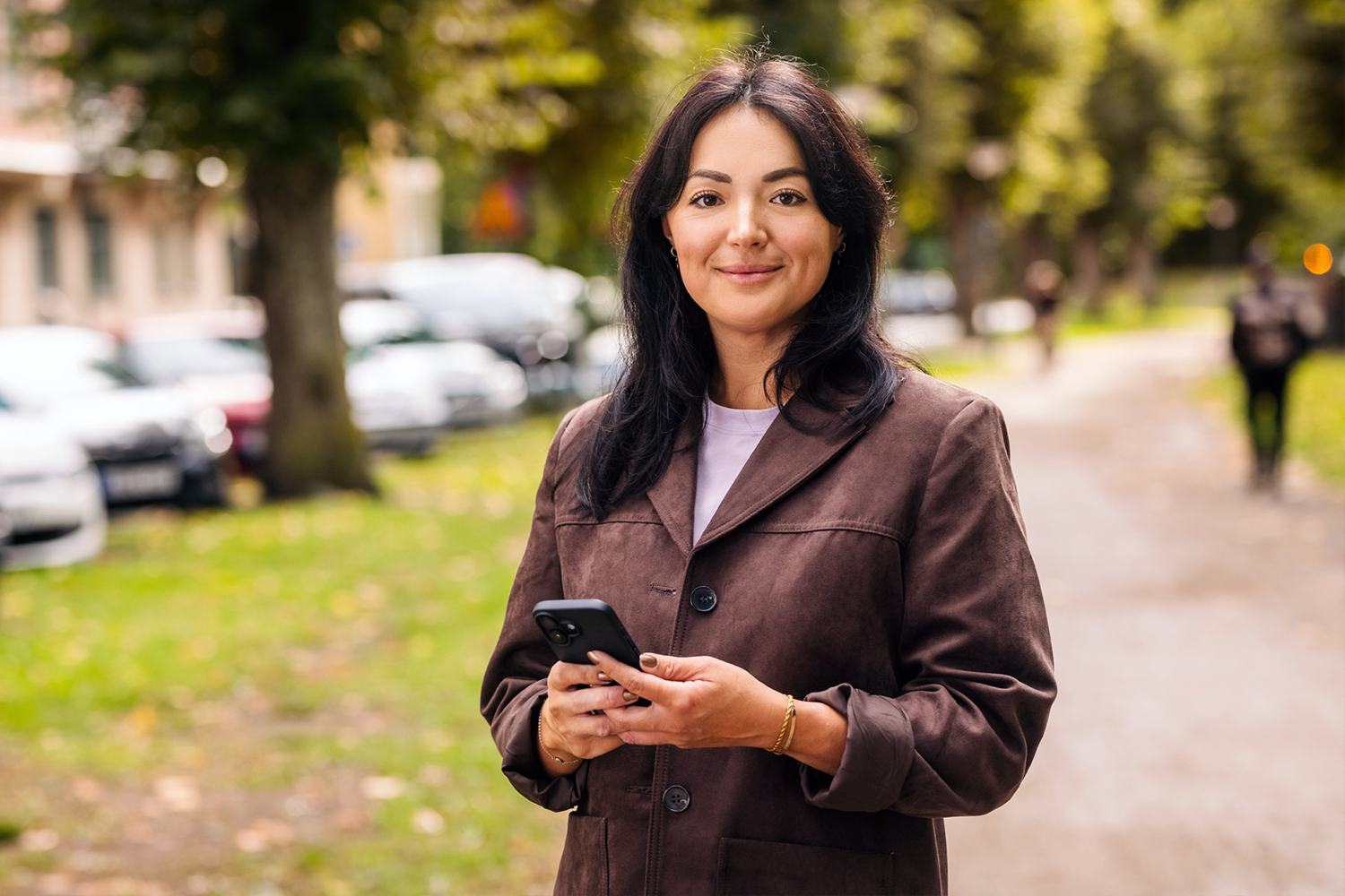 Kvinna håller i telefon och tittar in i kameran