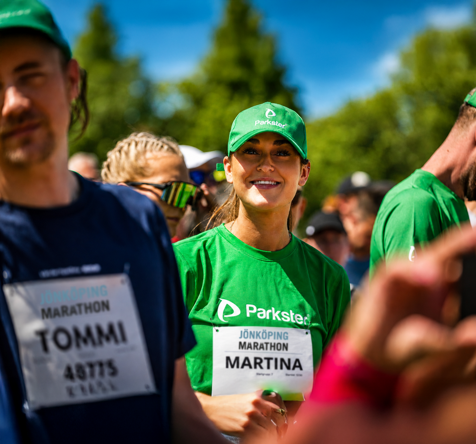 Glad kvinna med löparkläder, parkster logo på t-shirt och keps. soligt ute